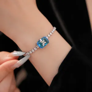 Dettaglio di un bracciale di lusso con zircone blu e farfalla micro-pave su catena tennis