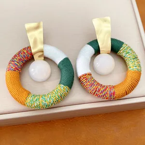 Close-up van bohemian ronde oorbellen met kleurrijk katoenen touw en hars kralen.
