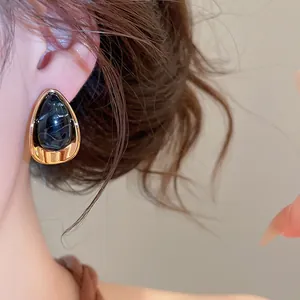 Gros plan d'une boucle d'oreille en acrylique en forme de larme avec cadre doré