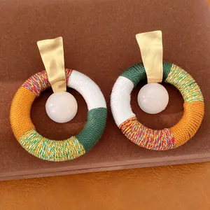 Detail van handgemaakte boho katoenen touw omwikkelde oorringen met witte hars kralen