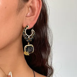 Detailopname van 18k vergulde zwarte zirkoon oorbellen gedragen door een model