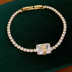 Dettaglio di un bracciale tennis dorato con zircone rettangolare e farfalla dorata