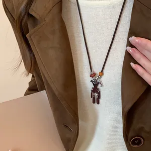 Nahaufnahme einer süßen braunen Bären-Anhänger-Halskette auf einem weißen Strickpullover.