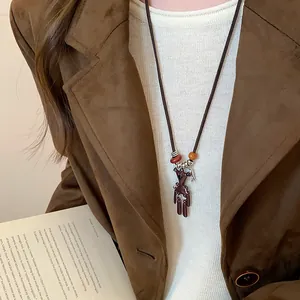 Detailansicht einer süßen braunen Bären-Halskette getragen auf einem Wildleder-Blazer.