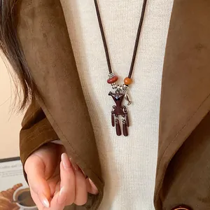 Nahaufnahme einer Halskette mit braunem Bärenanhänger auf einer braunen Wildlederjacke