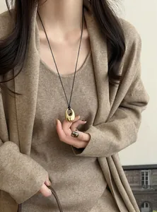 Elegante goldene Halskette mit ovalem Anhänger an schwarzer Kordel