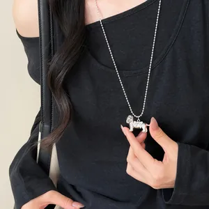 Gros plan d'un collier pendentif chiot en argent tenu pour montrer les détails fins.
