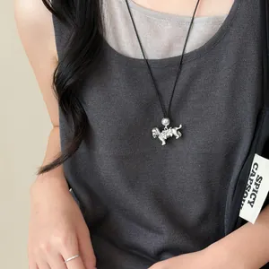 Gros plan d'un collier avec pendentif chien argenté, nœud et perle sur cordon noir