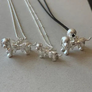 Vue détaillée de pendentifs chien en argent mat avec des nœuds sur différentes chaînes.