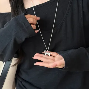 Détail du collier élégant avec pendentif chien teckel argenté porté sur un pull noir.
