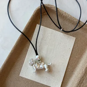 Détail exquis du collier pendentif chien en argent avec perle blanche et nœud décoratif