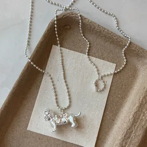 Vue détaillée d'un collier avec pendentif chien argenté et nœud sur un plateau