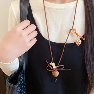 Detailed view of a cute handcrafted wooden dog pendant necklace worn over a black dress.