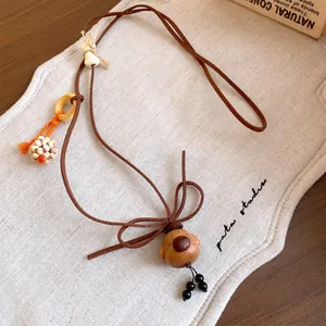 Detailed macro view of the handcrafted wooden dog pendant on a brown cord necklace.