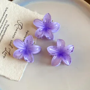 Vue détaillée de trois mini pinces à cheveux en acrylique violet en forme de fleur.
