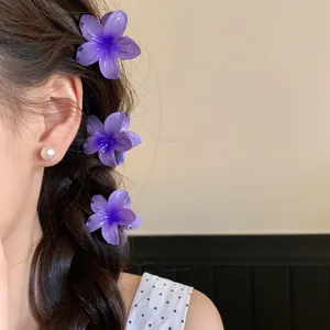 Gros plan de trois mini pinces à cheveux en acrylique violet sur une tresse.