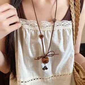 Detailed macro view of handmade wooden bear pendant necklace worn with a lace outfit.
