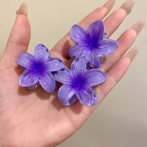 Gros plan de trois mini pinces à cheveux en acrylique en forme de fleur violette