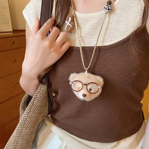 Nahaufnahme einer süßen Plüschbären-Halskette mit Brille auf einem Strickpullover
