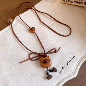 Detail of a vintage handcrafted wooden bear pendant on a natural brown adjustable cord.