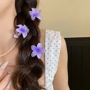Vue détaillée de trois mini pinces à cheveux fleurs en acrylique violet sur une tresse