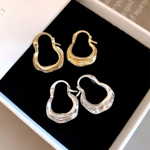 Close-up van getextureerde U-vormige creolen in goud en zilver in sieradendoos