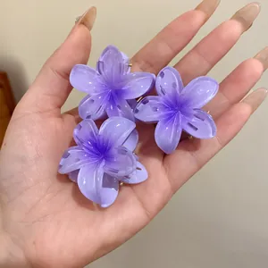 Gros plan de trois mini pinces à cheveux en acrylique violettes en forme de fleur