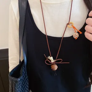 Close-up detail of a vintage wooden dog pendant necklace with bow accent worn over black clothing
