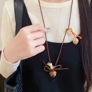 Detailed macro view of a retro wooden bear pendant necklace with a bow and tassel.