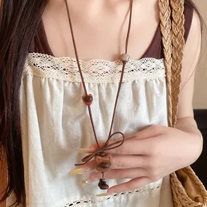 Detailed view of a vintage style wooden bear pendant necklace worn by a model on a dress