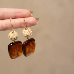 Close-up of French vintage raffia and amber acrylic square pendant hook earrings
