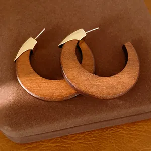 Gros plan de boucles d'oreilles vintage en bois en forme de C avec des accents dorés élégants.