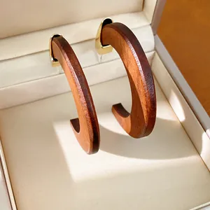 Gros plan de boucles d'oreilles créoles en bois vintage en forme de C avec clous dorés.