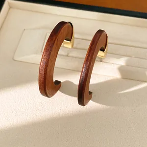 Détail des boucles d'oreilles en bois en forme de C avec grain naturel et métal doré