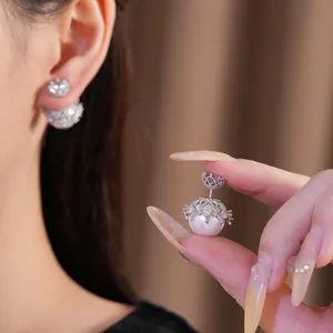 Detaillierte Makroansicht eines eleganten, zirkonbesetzten Perlenohrrings in den Fingern
