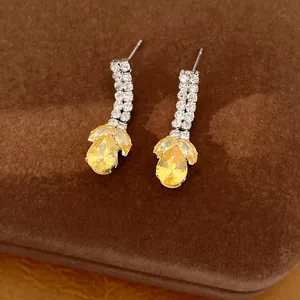 Detailaufnahme von eleganten Silberohrringen mit gelben tropfenförmigen Zirkonia-Steinen.