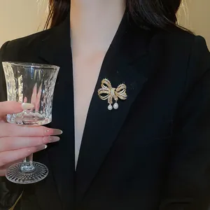Detailweergave van een fonkelende zirkoon strikbroche met parels op een zwarte blazerrevers