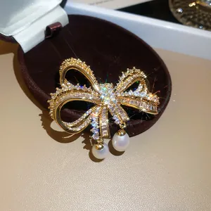 Detailopname van een fonkelende zirkoon strikbroche met elegante hangende witte parels