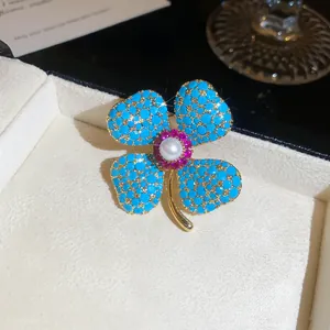 Detail van klavertje vier broche met turquoise kralen en een parel in het middenstuk.