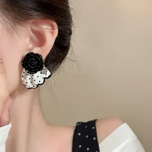 Detailed close-up showing elegant black rose earrings with polka dot ruffle design on model