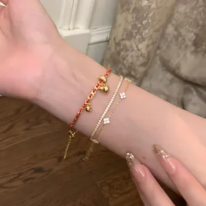 Primo piano di bracciali in zircone placcati oro 24K con catena a quadrifoglio al polso
