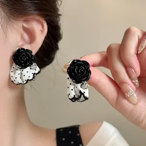 Detailed view of black rose earrings with polka dot lace fabric drop