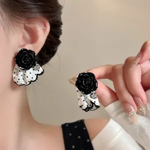 Detailed view of black rose earrings featuring white polka-dot fabric skirt
