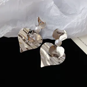 Detail van stijlvolle zilveren hartvormige oorbellen met mooie witte parelaccenten