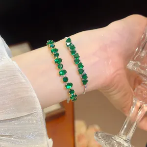 Close-up of elegant 18k gold plated bracelets with sparkling green heart zircons