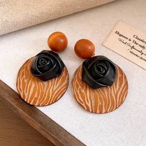 Close-up of retro wooden earrings with black rose detail and wood grain pattern
