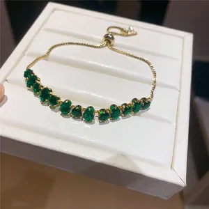 Macro detail of elegant 18k gold-plated bracelet featuring sparkling green oval gemstones