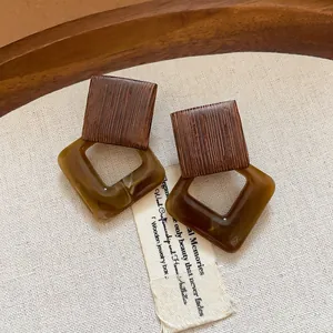 Detailed shot of vintage-style square earrings with wood texture and olive green resin
