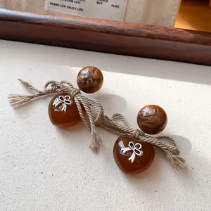 Primo piano di orecchini vintage a cuore in ambra con fiocco d'argento e perno marmorizzato.