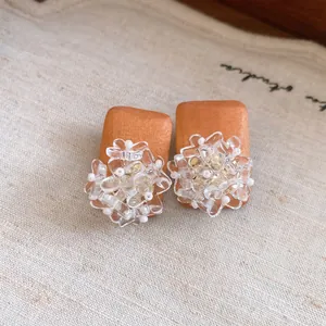 Close-up detail of retro square wood stud earrings with transparent floral resin accents